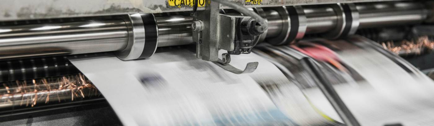 Wide-format press running a printed sheet through the rollers